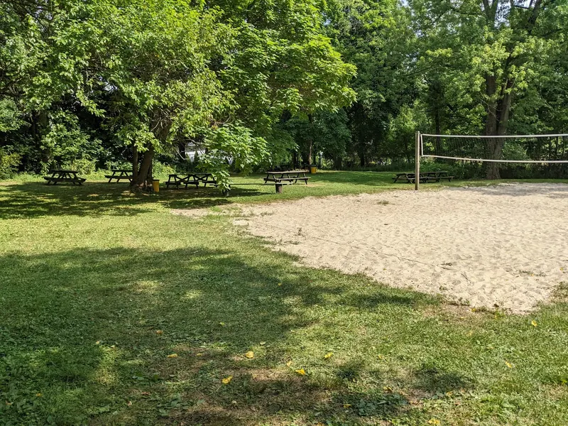 Shaded picnic tables and sand volleyball court on the Hopewell Quarry grounds