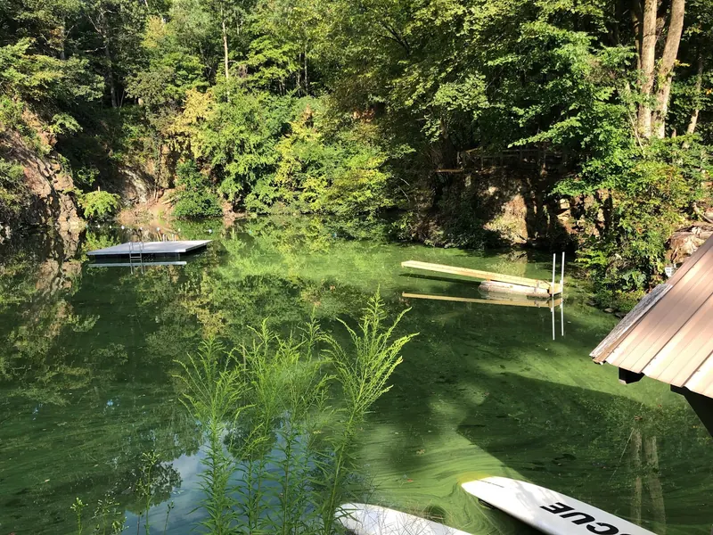 Tree-lined Hopewell Quarry water with floating platforms and a diving board