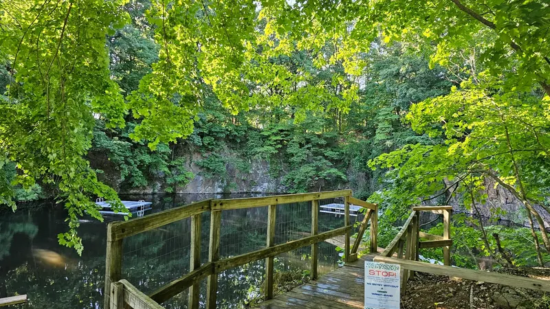 Wooden railing and steps above Hopewell Quarry with a historical swim-test wristband sign