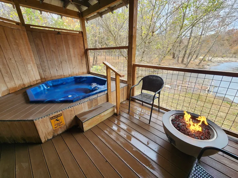 Blue mineral bath on a covered wooden deck with steps, a slippery-surface warning and waterway view