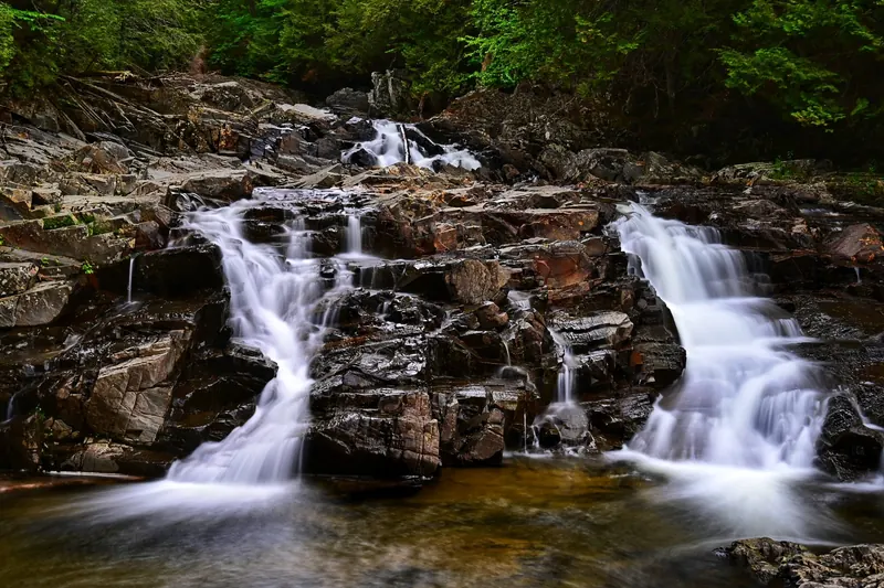 Historical Houston Brook Falls cascade over dark layered rock in a wooded setting