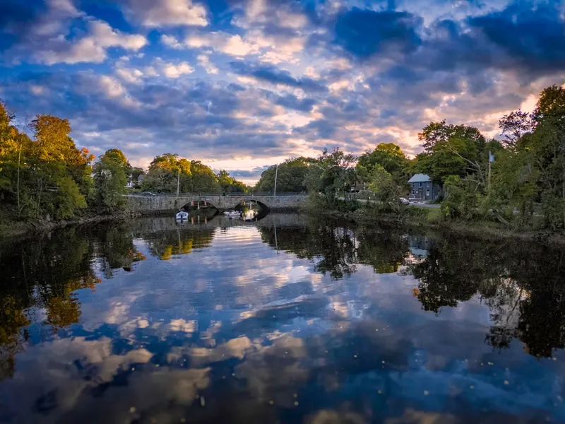 Stone bridge reflected in the Ipswich River at sunset, shown as general river scenery