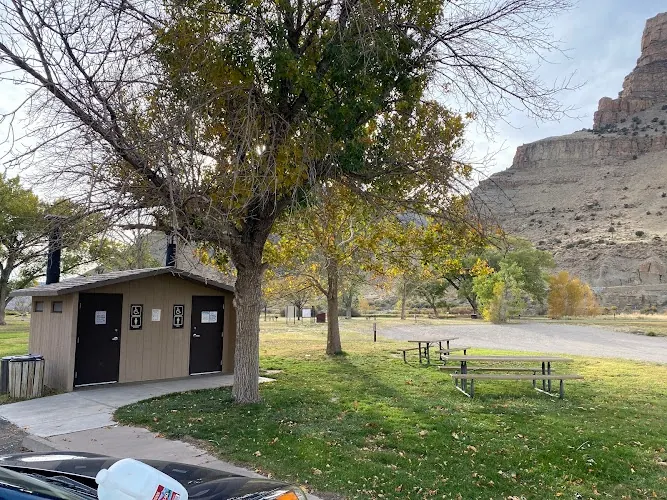 Restroom building and picnic tables beneath trees and canyon cliffs in the Island Acres park collection