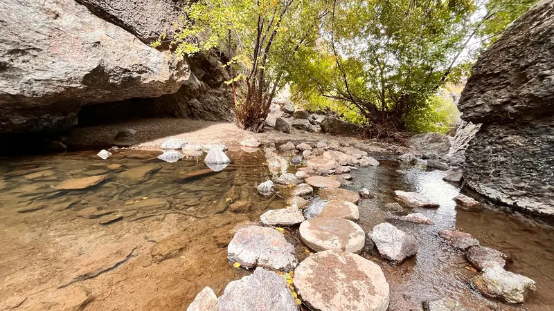 Rocks crossing shallow water between canyon walls at Jump Creek; a past scene, not a verified crossing route