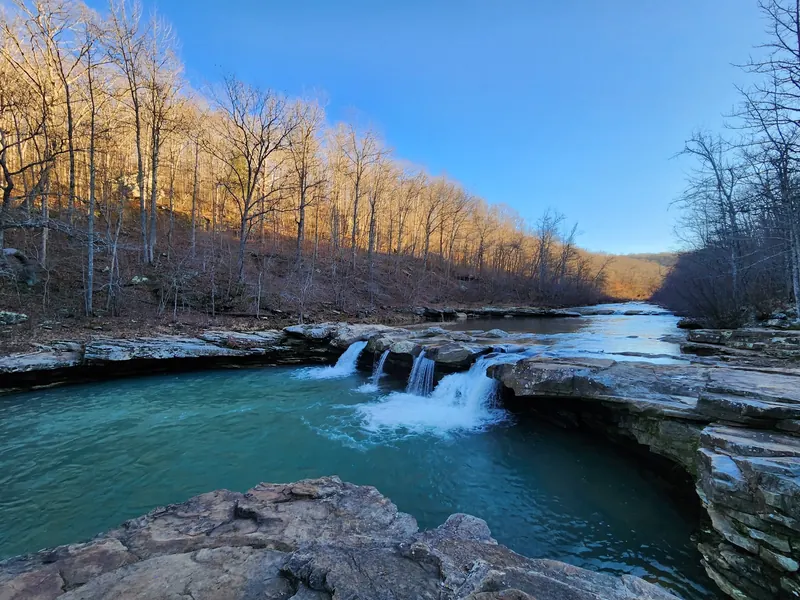 Multiple cascades at Kings River Falls with leafless wooded banks; seasonal landscape context, not a current flow report