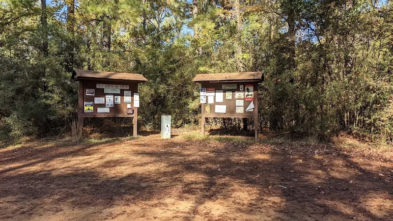 Two wooden visitor information boards and a self-service post among trees at the Kisatchie Bayou recreation collection