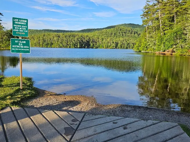 Lake Luzerne viewed from the Wayside collection's launch ramp with boating restriction signs and wooded hills