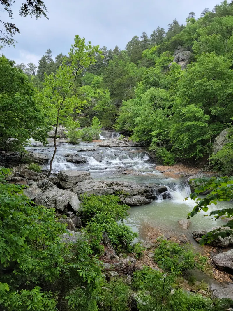 Layered cascades at Little Missouri Falls among wooded banks; a separate waterfall destination, not Albert Pike or a verified safe swimming entry