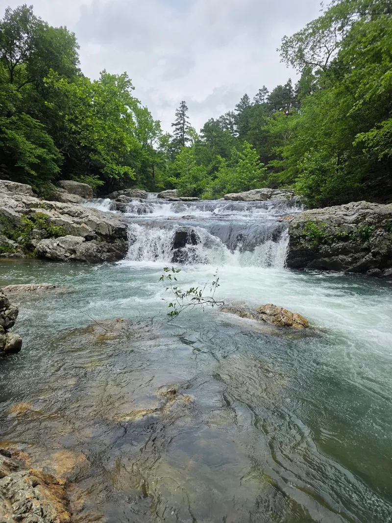 Broad whitewater cascade and exposed foreground rocks in the Little Missouri Falls collection; historical flow, not proof of current swimming safety