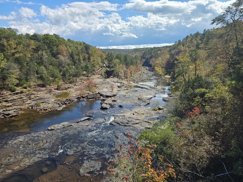 Rocky river channels and wooded banks in Little River Canyon with distant visitors; historical conditions