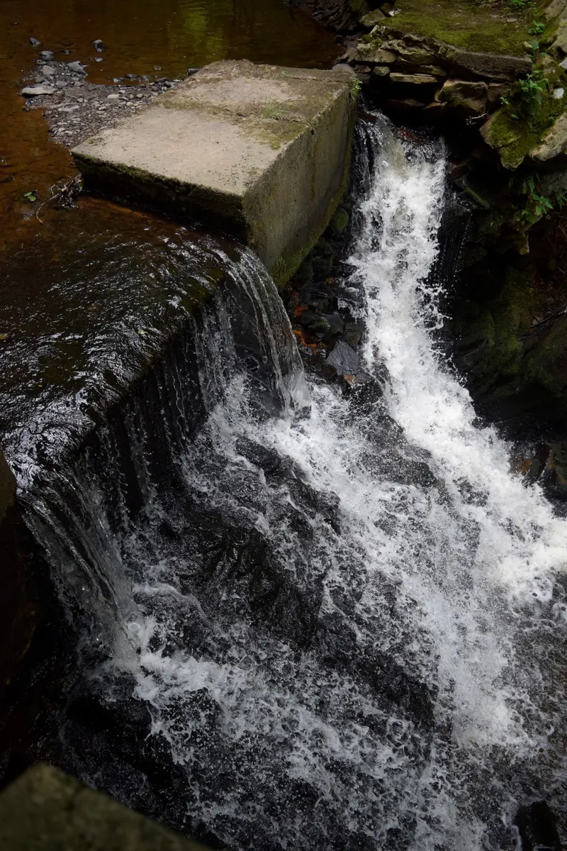 Close view of water flowing beside a concrete block and dark rock in the Little Shickshinny Creek photo collection