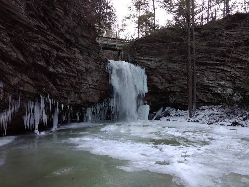 Ice and snow surrounding Little Stony waterfall beneath the footbridge in a winter photograph