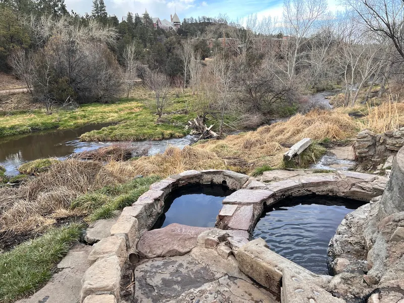 Empty stone-lined soaking pools beside a river in the Montezuma Hot Springs collection; historical layout, not current water-condition evidence