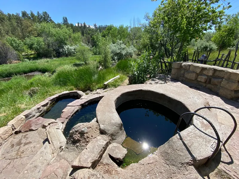 Empty circular soaking tub beside stone-lined pools at Montezuma Hot Springs