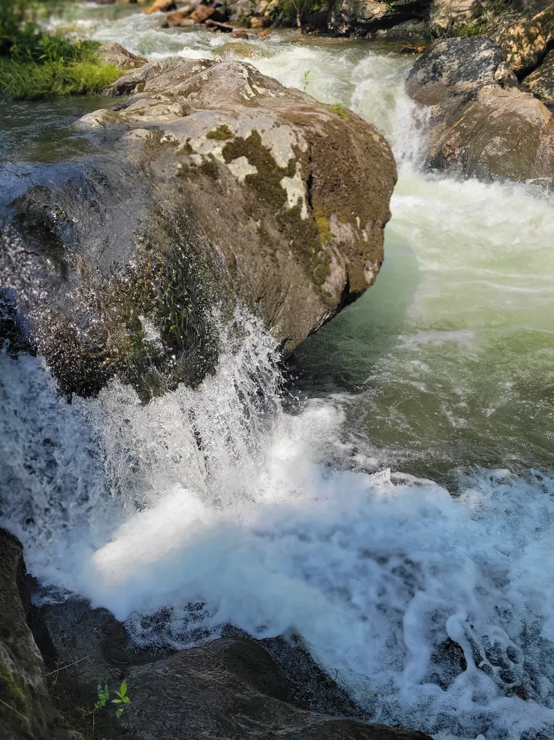 Rushing water beside large mossy rocks at Mount Hope Park