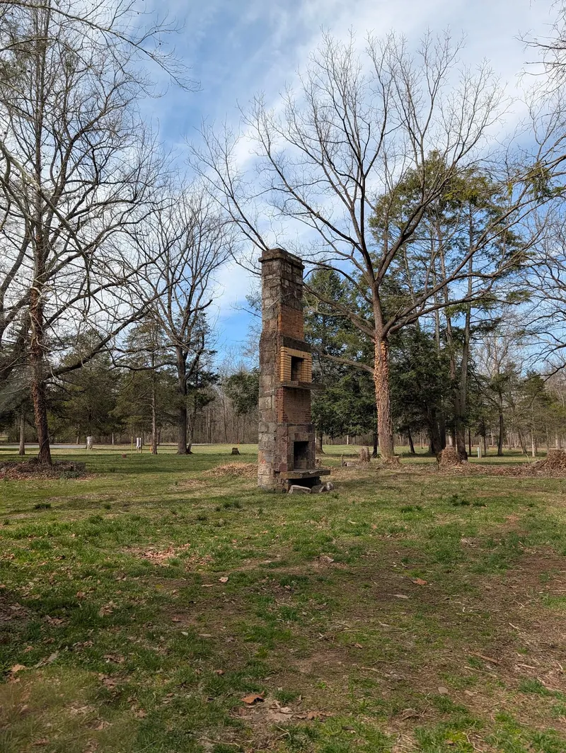 Freestanding masonry chimney on wooded grounds in the Natural Chimneys Park collection, distinct from the geological towers
