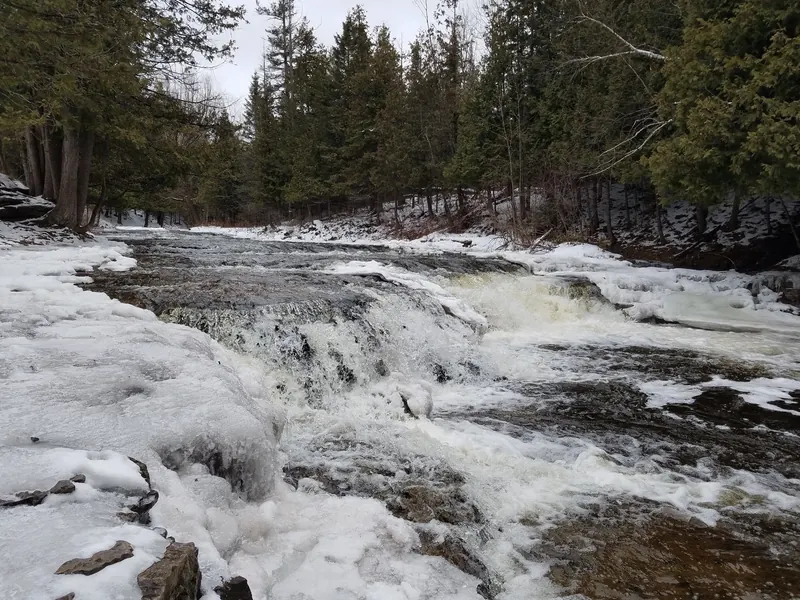Ocqueoc Falls in winter with snow and ice along the riverbanks
