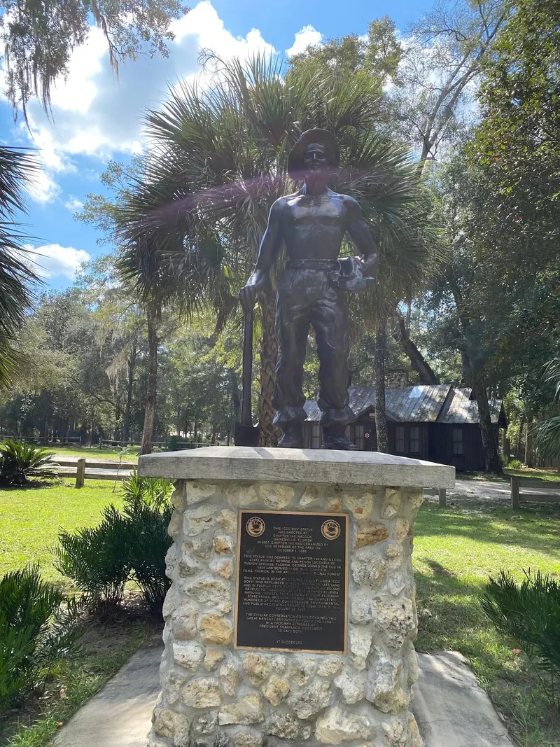 Civilian Conservation Corps worker statue on a stone pedestal at O'Leno State Park; historical park context