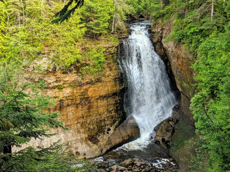 Waterfall flowing through a steep forested rock channel in the Pictured Rocks collection