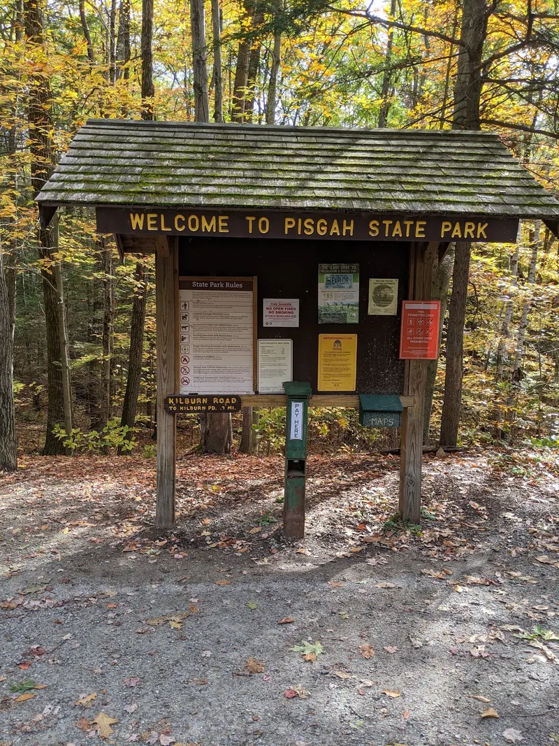 Pisgah State Park welcome kiosk with a Kilburn Road sign amid autumn trees