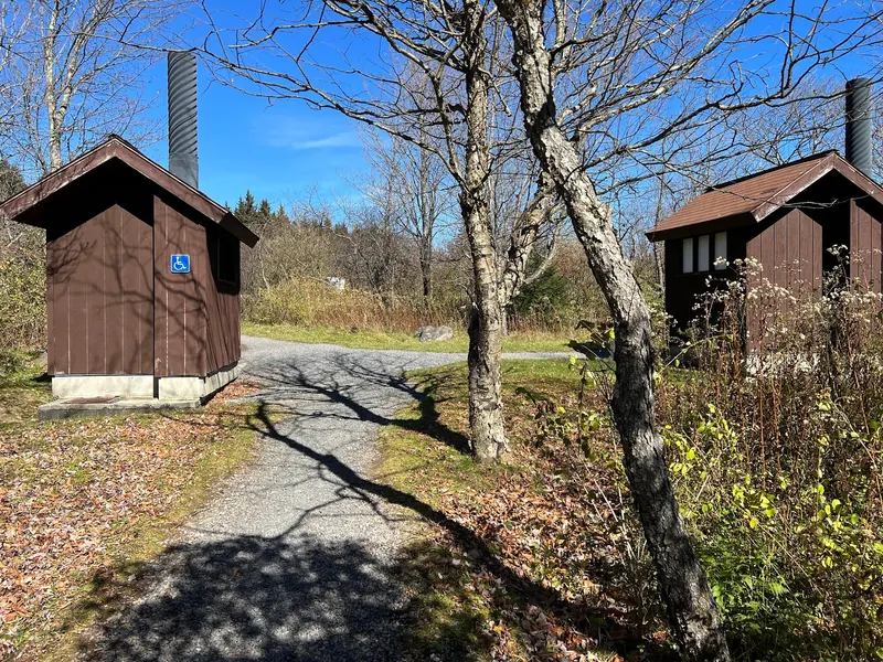 Toilet buildings with an accessibility symbol at Red Creek Campground; historical facility view, not an accessible creek swimming entry