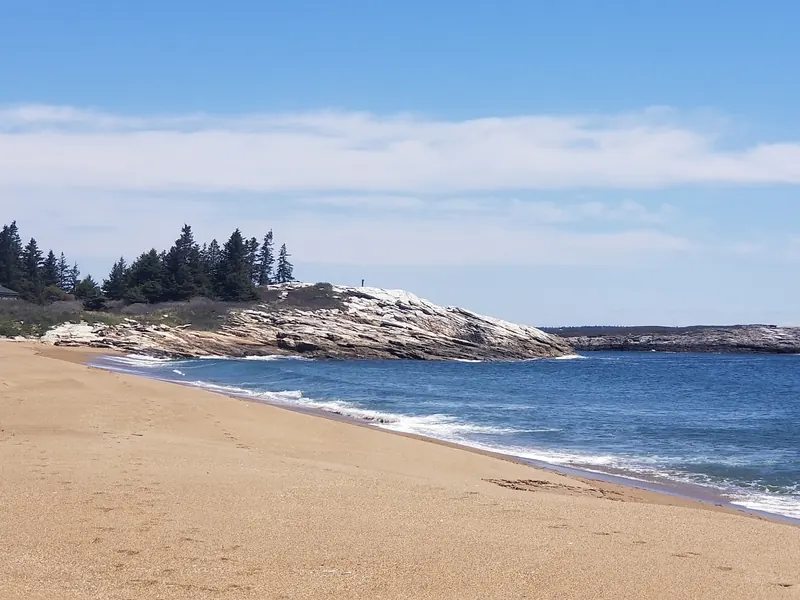 Sandy Reid State Park shoreline beside blue ocean water and a pale rocky headland in a historical photo