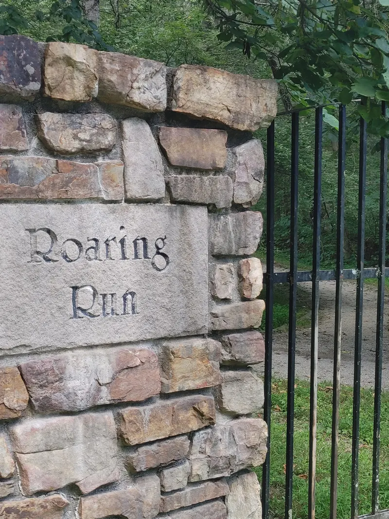 Stone entrance pillar marked Roaring Run beside a metal gate
