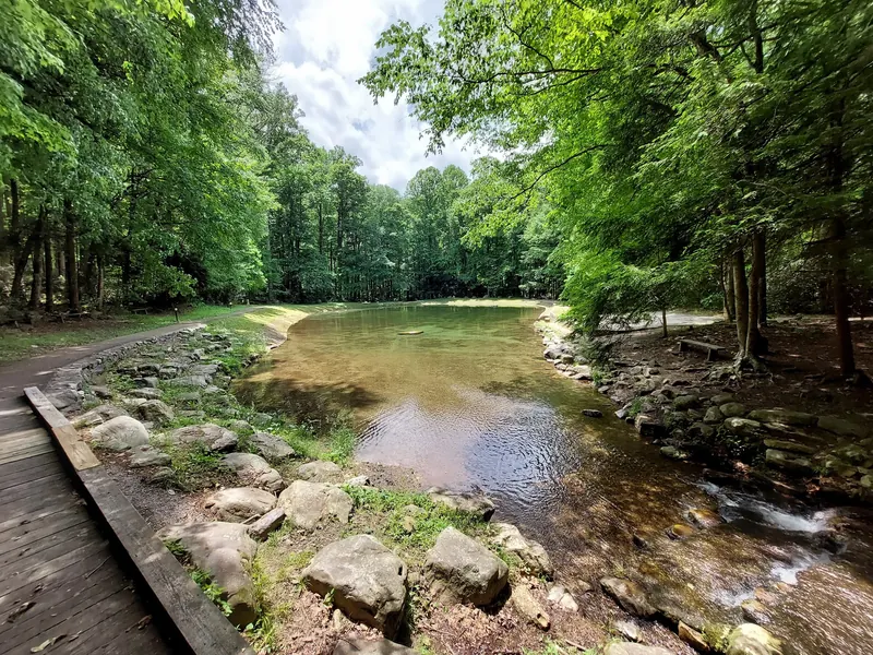 Creek-fed developed pond with concrete banks and a wooden bridge at Rock Creek Recreation Area