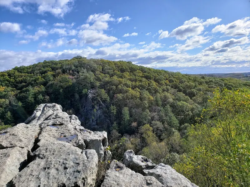 Rocky overlook above a forested valley at Rocks State Park beneath a blue sky