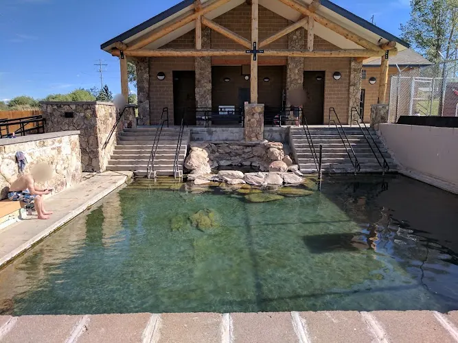 Saratoga public Hobo Pool with stone-edged water, entry stairs and bathhouse; visitors' faces blurred
