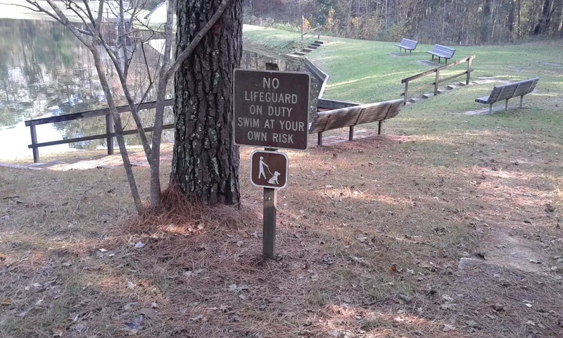 Historical no-lifeguard warning beside Shongelo Lake and shoreline benches