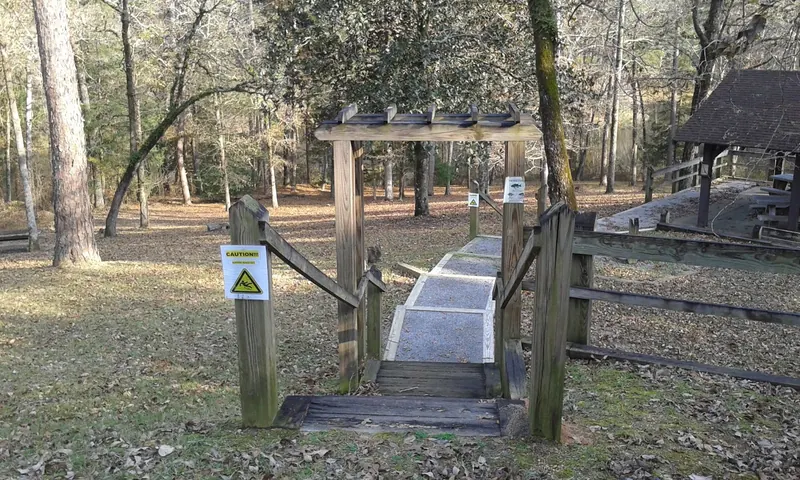 Timber walkway at Shongelo with caution notices beside wooded picnic grounds