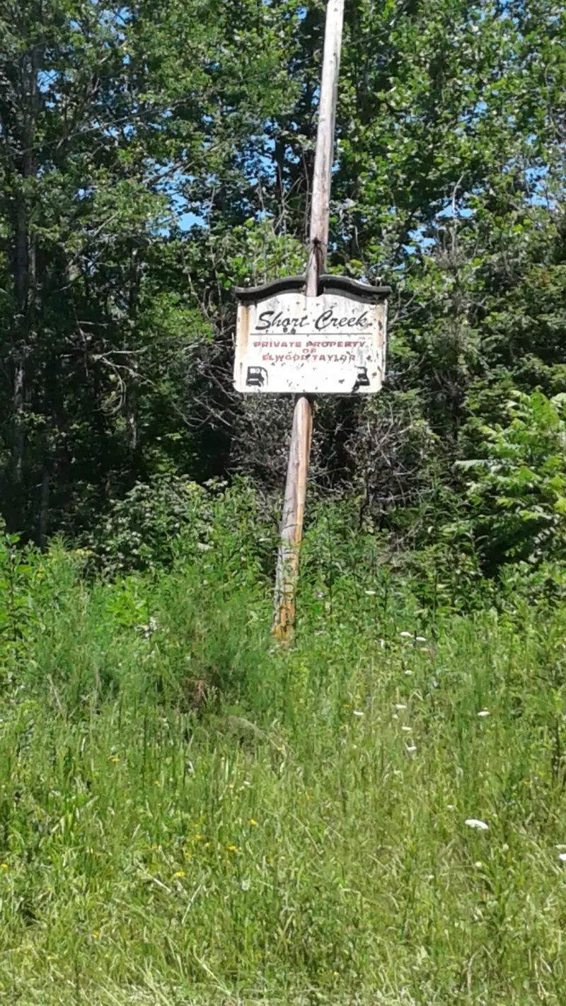Short Creek sign identifying private property beside a wooded roadside