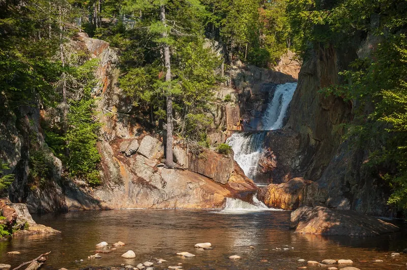 Tiered waterfall descending through a wooded rock gorge at Smalls Falls, Maine