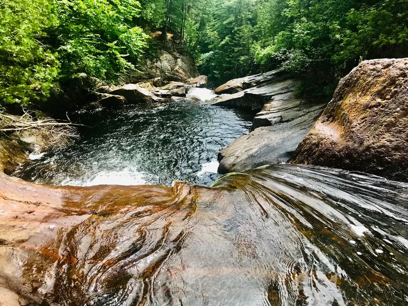 Water flowing over smooth rock ledges into a pool at Smalls Falls