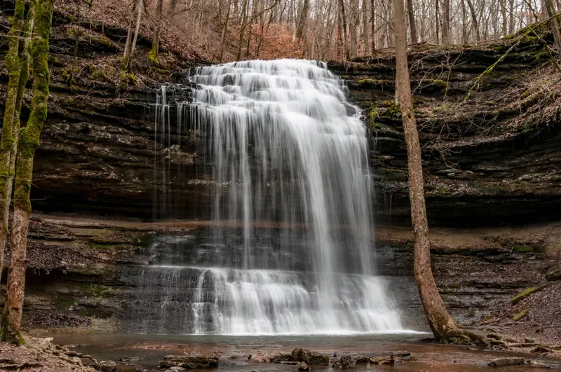 Stillhouse Hollow Falls cascading over layered rock into the wooded hollow