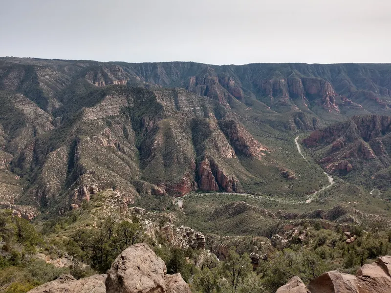 Broad canyon panorama with layered red cliffs and a winding wooded valley in the Sycamore Canyon collection; scenery, not a swimming-entry guide
