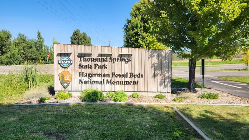 Shared Thousand Springs State Park and Hagerman Fossil Beds entrance sign beside visitor-center parking