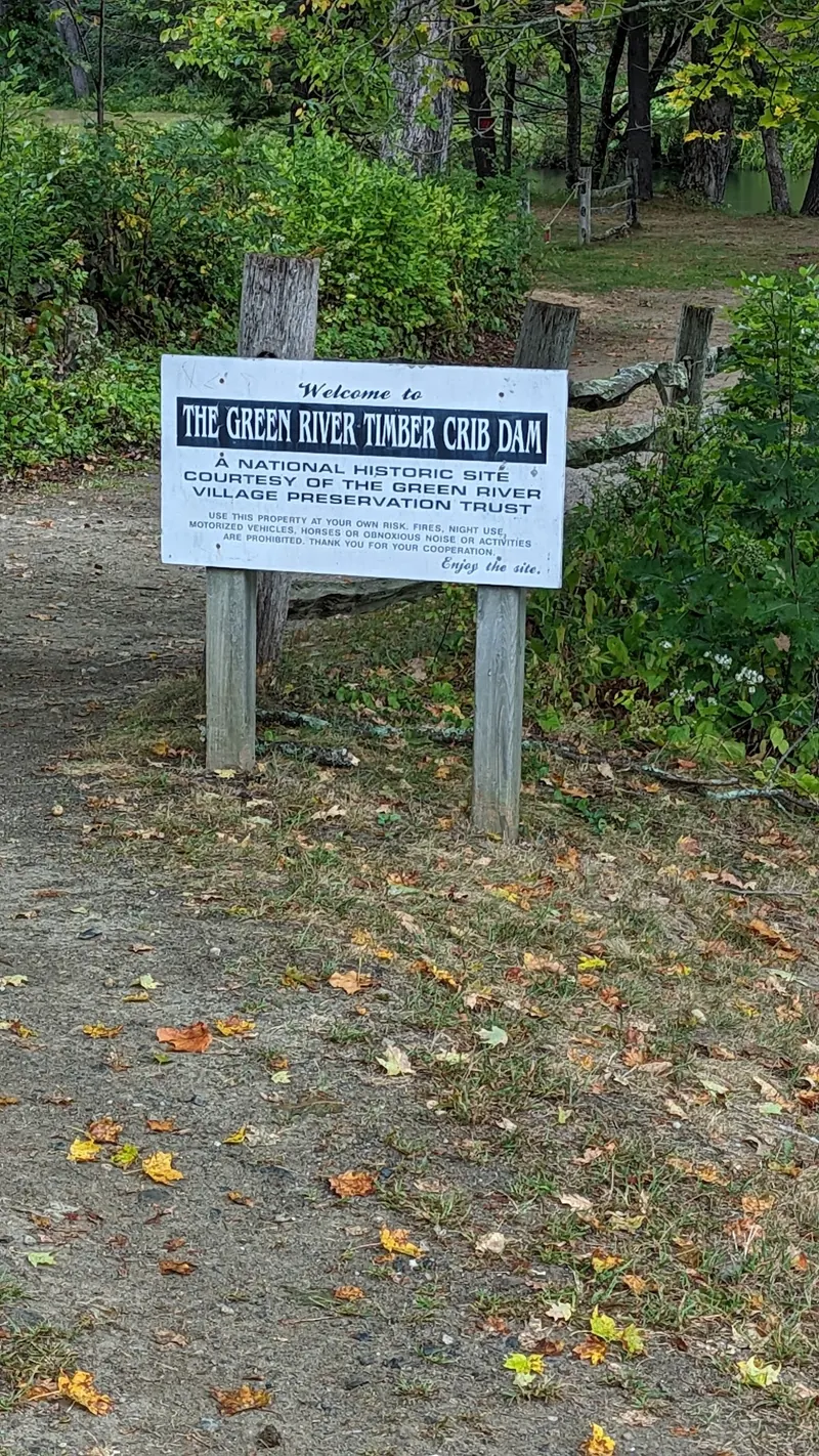 Green River Timber Crib Dam welcome sign naming the Village Preservation Trust beside a path