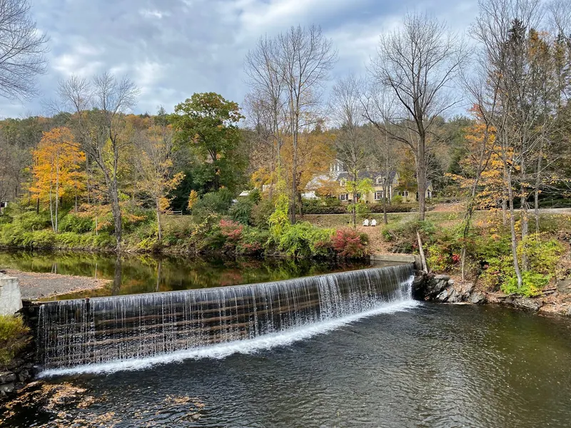 Water flowing over the Green River timber crib dam beneath autumn trees