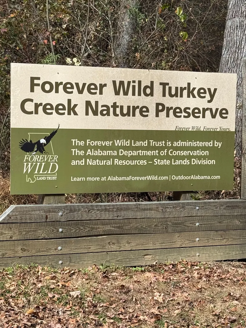 Forever Wild Turkey Creek Nature Preserve sign beside a wooden bench
