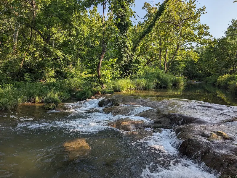 Small creek cascade flowing across rock among woodland in the Turner Falls collection