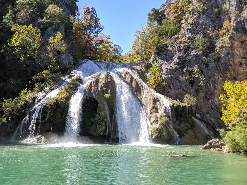 Turner Falls waterfall spilling over rock into the pool beneath wooded cliffs