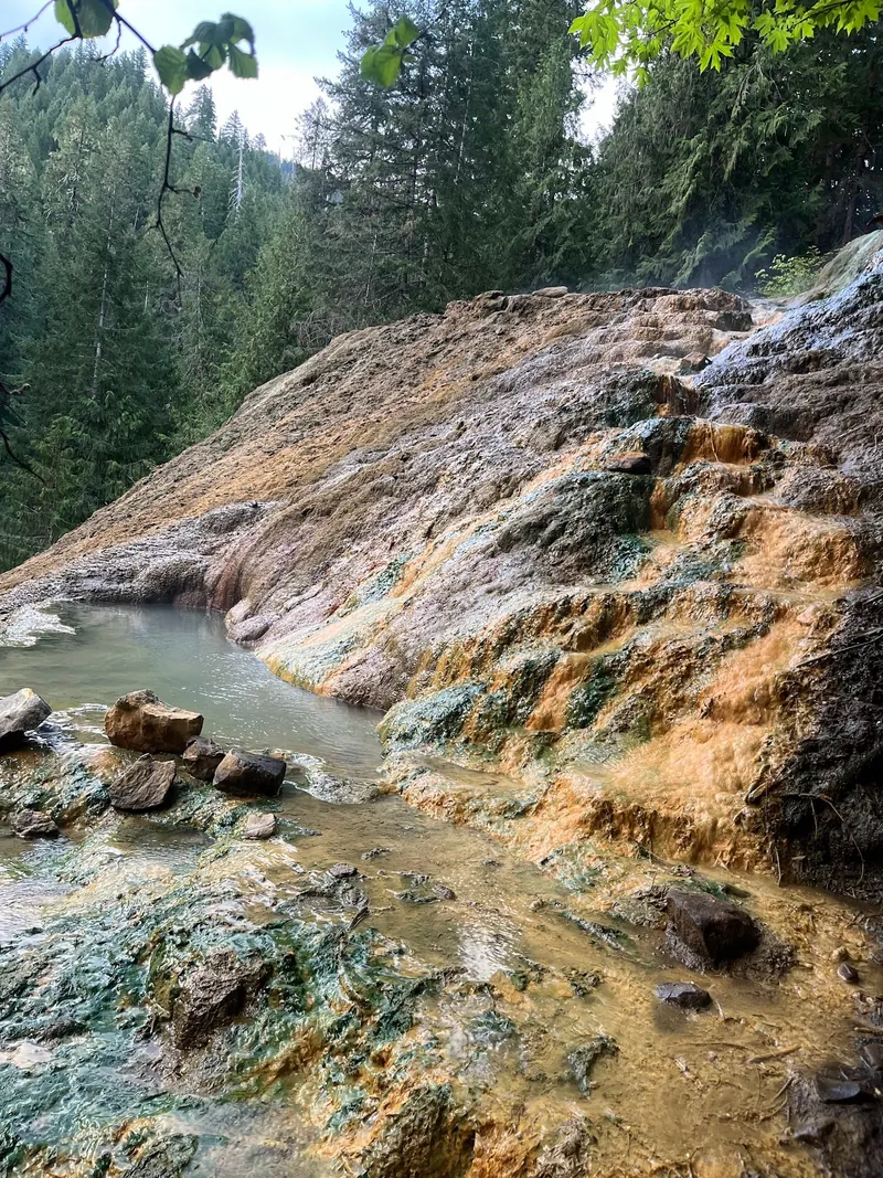 Mineral-stained slope and empty soaking pools at Umpqua Hot Springs