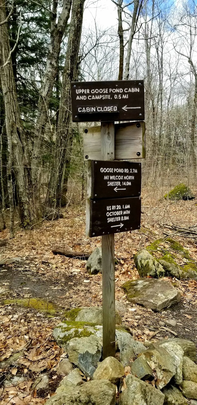 Historical Upper Goose Pond Cabin junction sign showing a half-mile side trail and cabin-closed marker, not a live status report