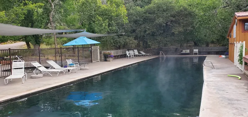 Empty rectangular soaking pool beside a wooden bathhouse at Valley View Hot Springs