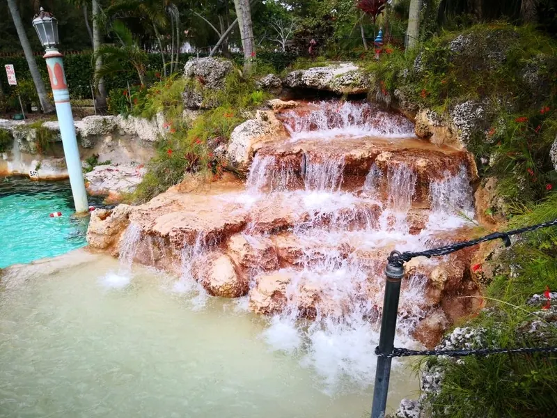 Historical water cascading over coral-colored rocks beside Venetian Pool; not current water conditions