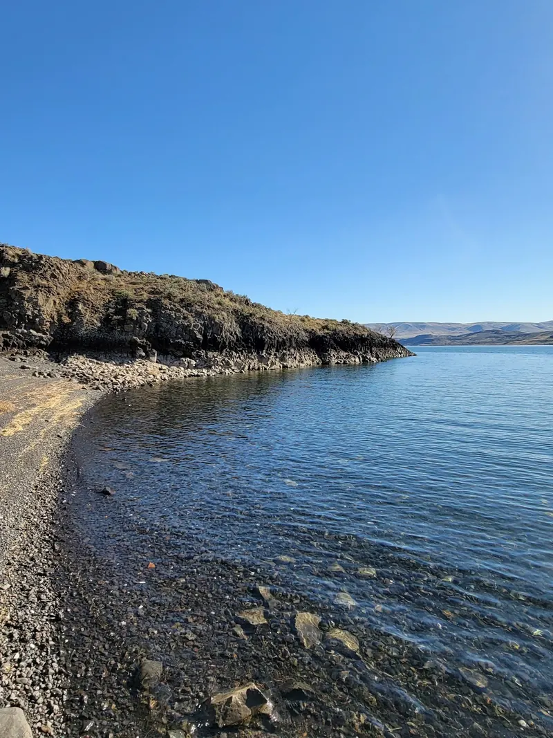 Rocky shoreline and low cliffs beside Wanapum Lake; general reservoir scenery, not a verified view of the historic swimming cove