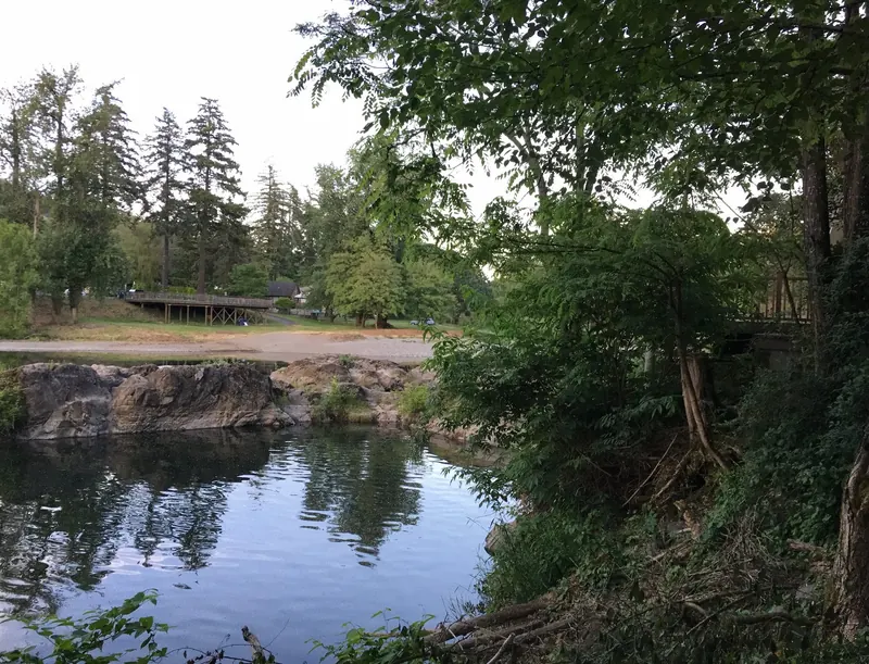 Washougal River beside rocks and trees at Sandy Swimming Hole Park, with the beach and raised viewing deck across the water