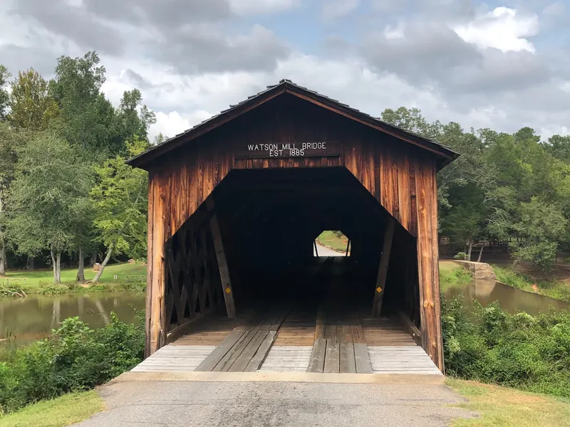 Wooden entrance of Watson Mill Bridge with its name and 1885 date above the roadway; historical landmark context